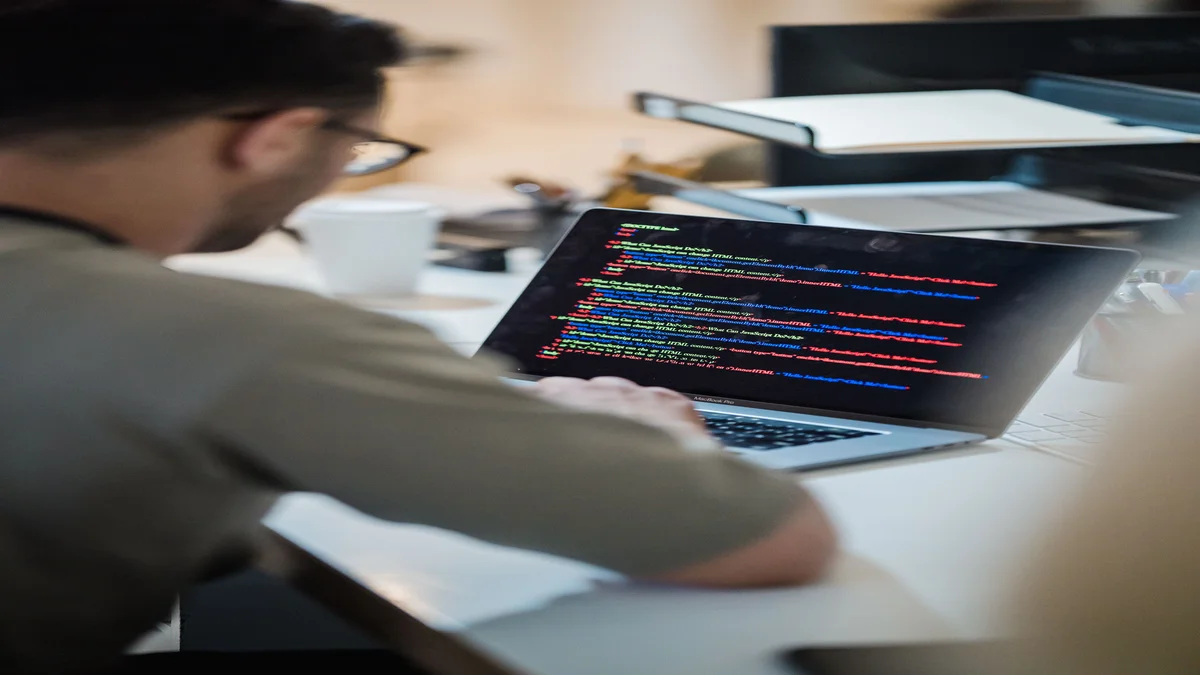 Programador focado digitando codigo em laptop, representando uso do Claude Code com Opus 4.8