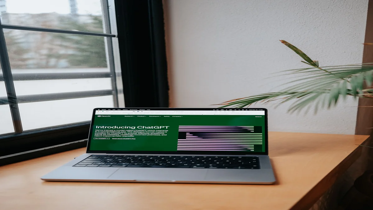 Notebook aberto sobre mesa exibindo a interface de uma IA conversacional, ao lado de uma janela