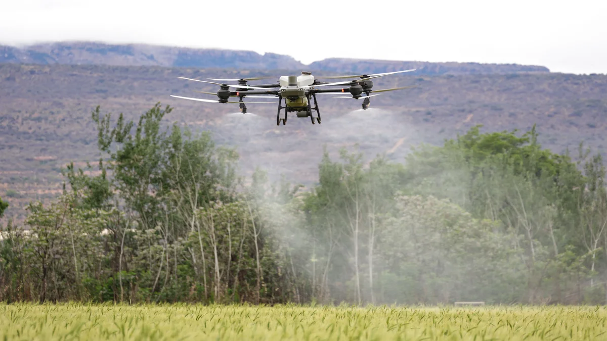 Drone agrícola de alta tecnologia pulverizando uma lavoura, com montanhas ao fundo