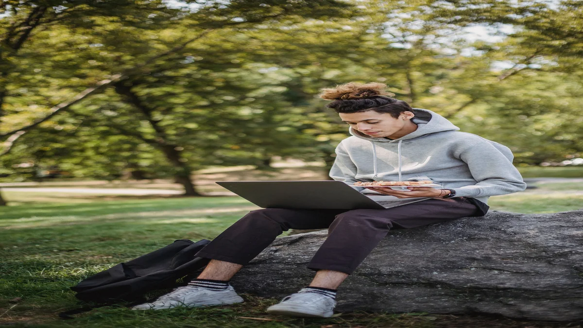 Jovem estudante revisando conteudo com notebook e caderno, representando estudo com apoio de inteligencia artificial