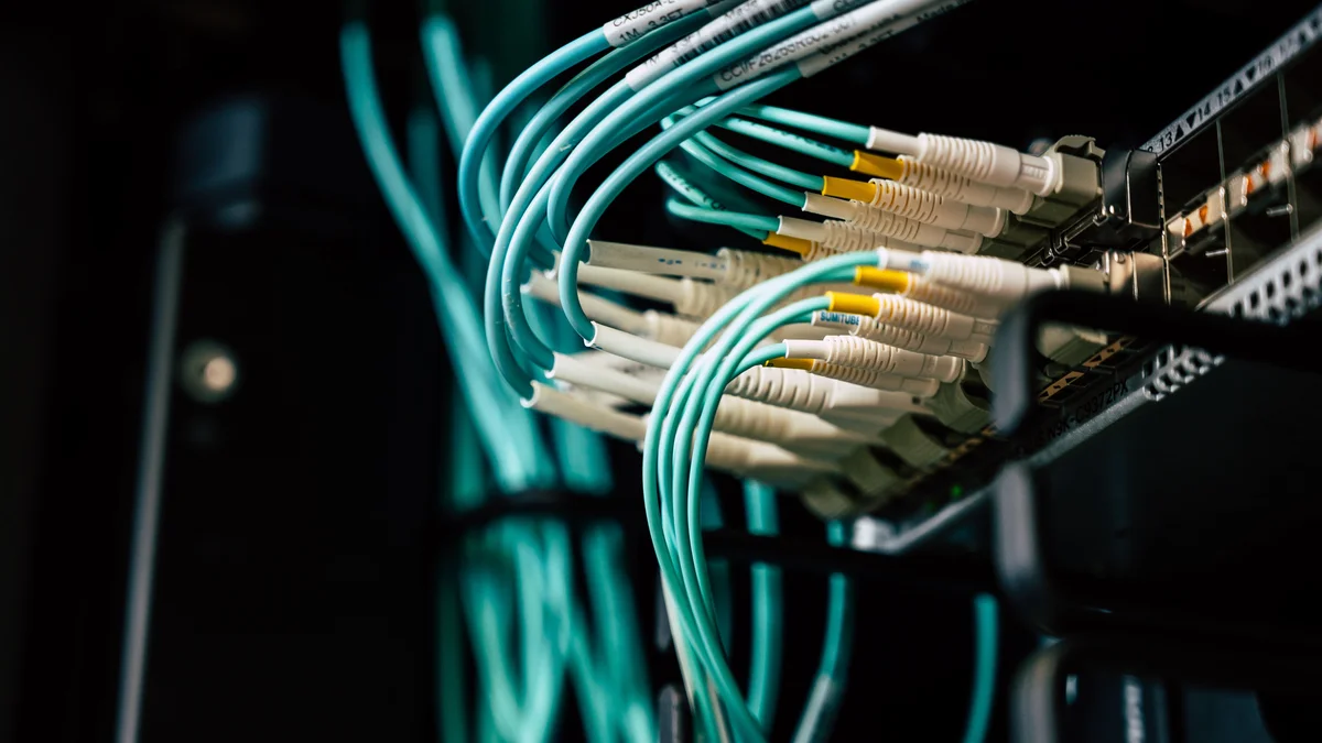 Cabos de rede conectados a um rack de servidor em data center, representando falha de configuracao de rede