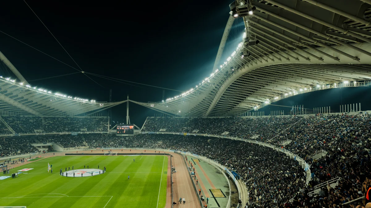 Estadio de futebol lotado e iluminado a noite durante partida, cenario que remete aos jogos monitorados por sistemas de IA contra manipulacao de apostas